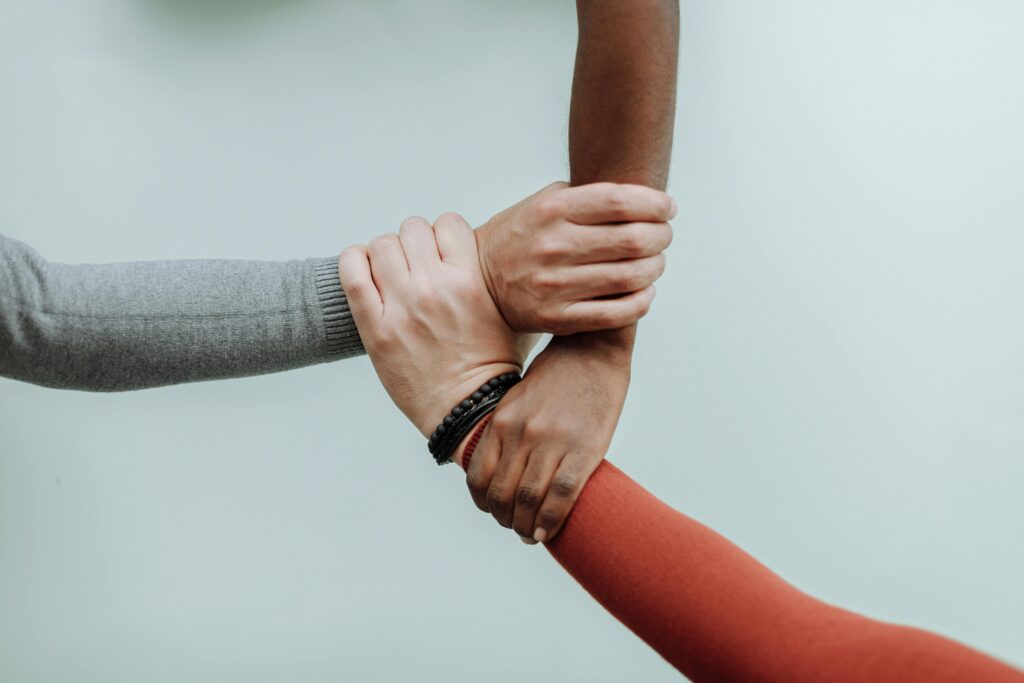 A photo of three hands interlocked representing Buddhist interdependence